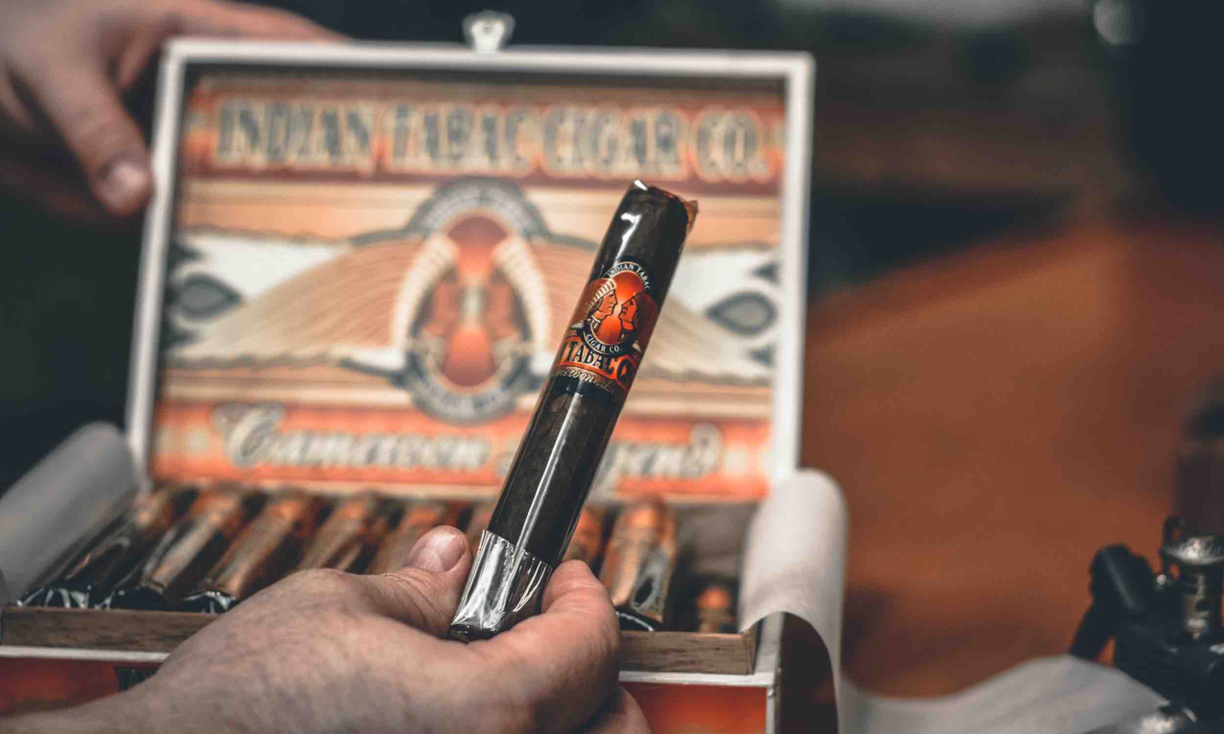 Image of a cigar being held near a box of cigars